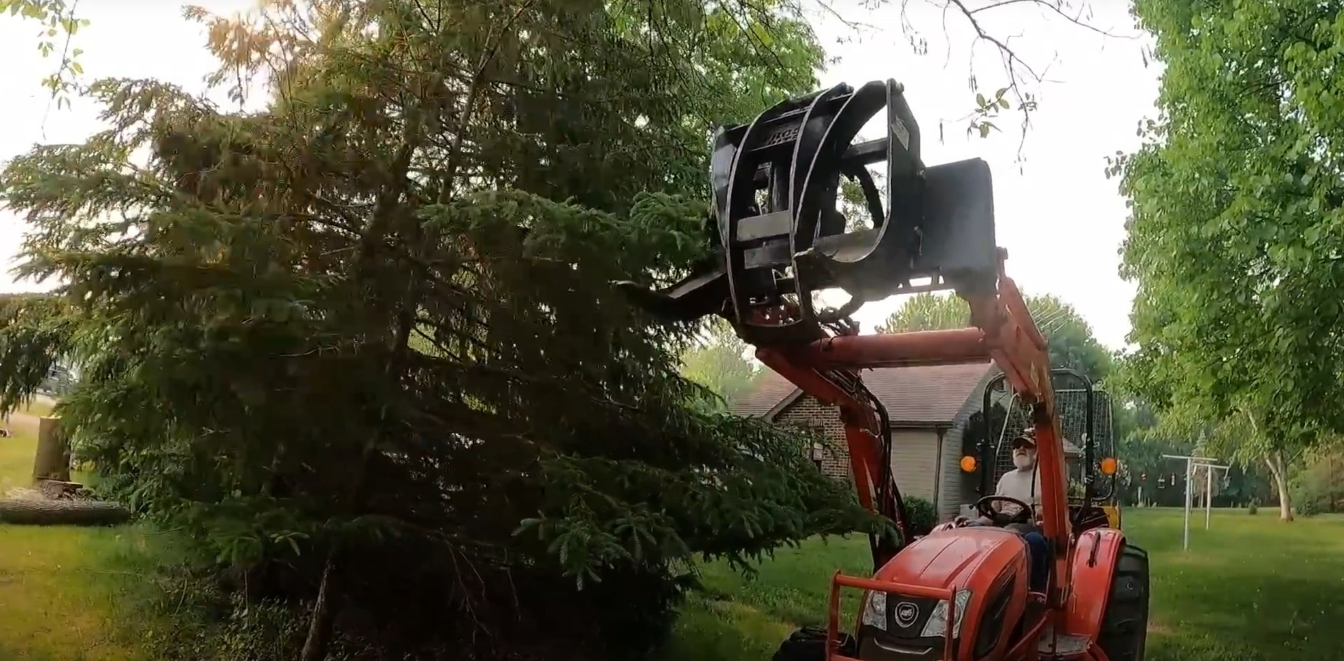 Heavy machinery removing fallen tree from residential property